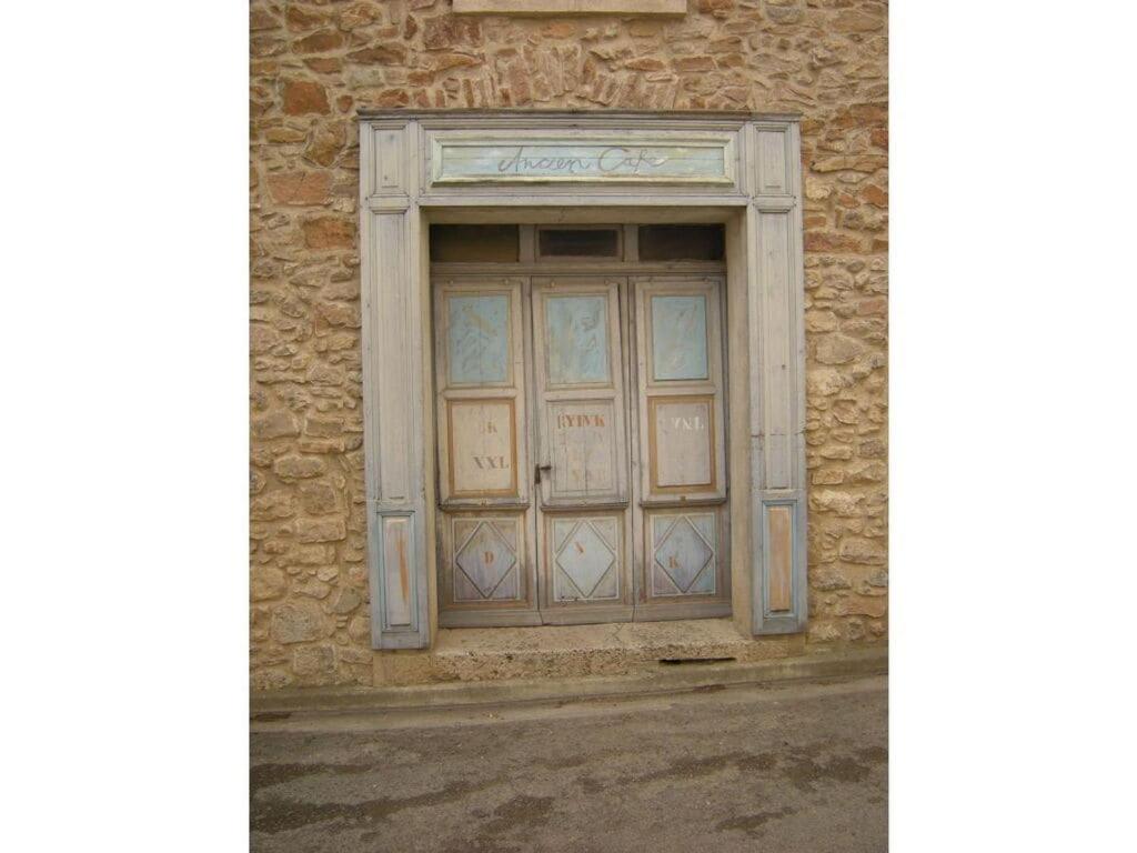 - un bâtiment en pierre avec une grande porte en bois dans l'établissement "Ancien Cafe" with roof terrace and balcony, à Camplong-dʼAude 14 autres photos