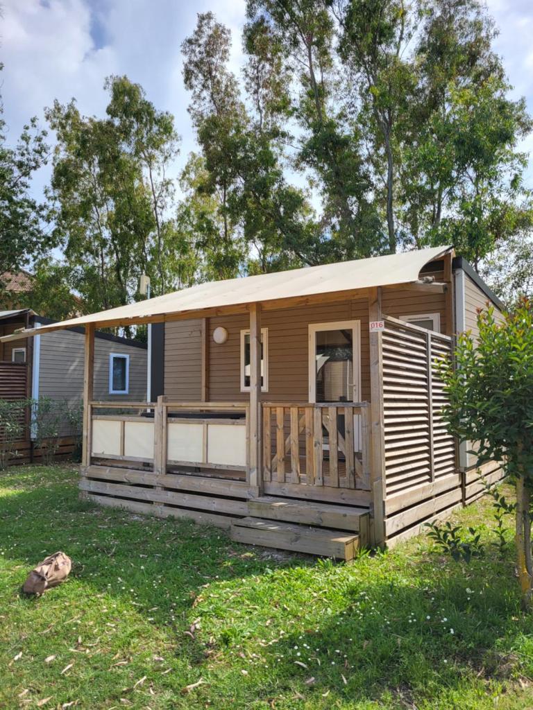 une cabine avec terrasse couverte dans une cour dans l'établissement Mobil home 4 personnes climatisé, à Hyères