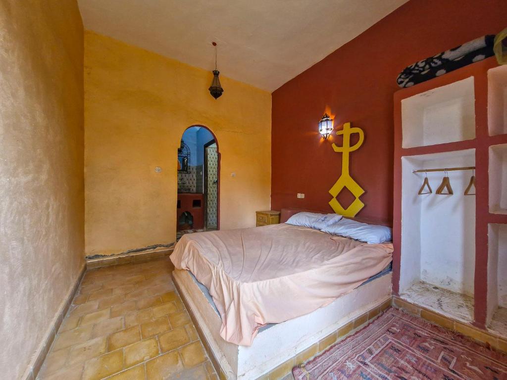 - une chambre dotée d'un lit avec une croix sur le mur dans l'établissement Riad Akour, à Merzouga