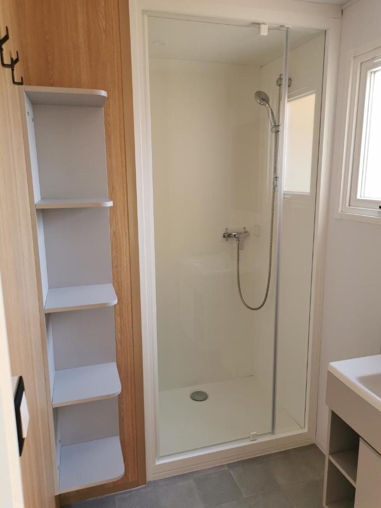 La salle de bains est pourvue d'une douche et d'étagères blanches. dans l'établissement tony vacances, à Martigues