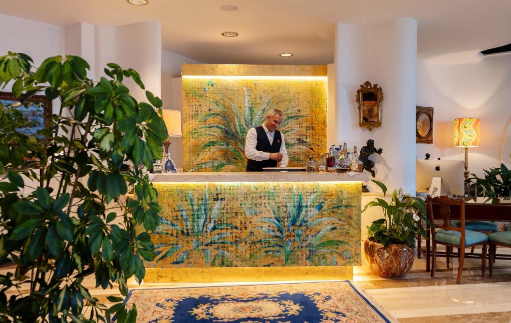 un homme debout dans un bar dans une pièce avec un tableau dans l'établissement Hotel Le Agavi, à Positano 115 autres photos