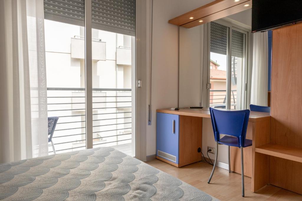 une chambre avec un lit, un bureau et une chaise bleue dans l'établissement Hotel Riviera, à Caorle 118 autres photos