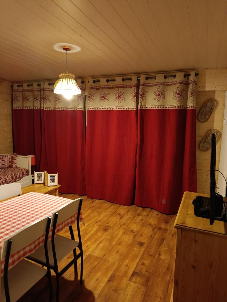 - un salon avec des rideaux rouges et une table dans l'établissement Appartement Paisible, à Briançon