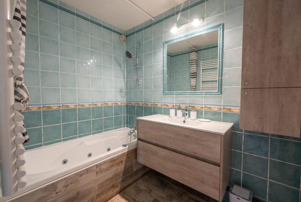 une salle de bain avec un lavabo, une baignoire et un miroir dans l'établissement Echo des marmottes - Au pied des pistes - Parking, à Enchastrayes 15 autres photos