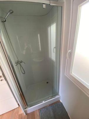 une douche avec une porte vitrée dans une salle de bain dans l'établissement camping la marina, à Canet