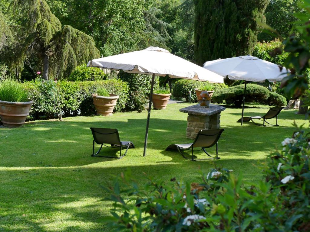 un groupe de chaises et de parasols dans une cour dans l'établissement Villa Campo di Fiore, à Arezzo