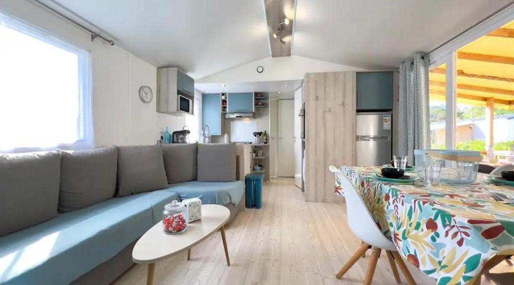 un salon avec un canapé bleu et une table dans l'établissement CAMPING Siblu Le Montourey - LE FARNIENTE, à Fréjus