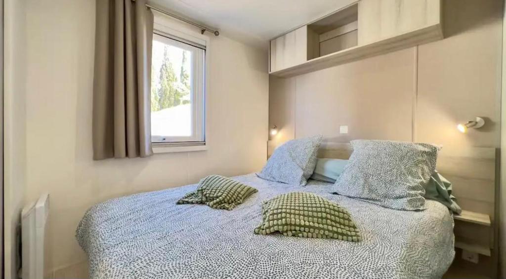 une chambre avec un lit avec des oreillers et une fenêtre dans l'établissement CAMPING Siblu Le Montourey - LE FARNIENTE, à Fréjus