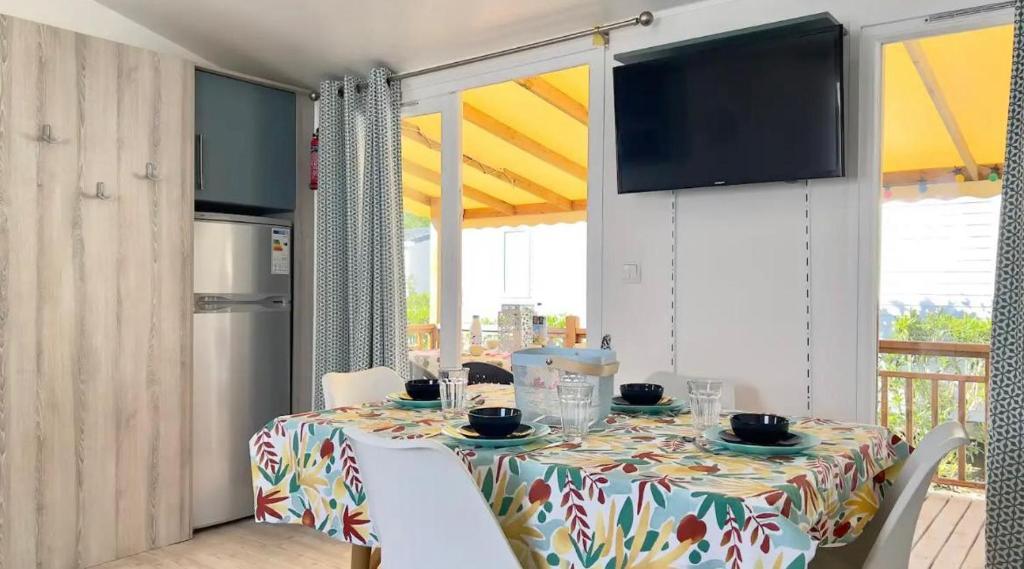 une salle à manger avec une table avec des chaises et une télévision dans l'établissement CAMPING Siblu Le Montourey - LE FARNIENTE, à Fréjus