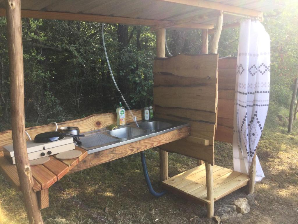 un évier dans un gazebo avec une cuisinière dans l'établissement La roulotte du bonheur, à Saint-Pardoux-la-Rivière