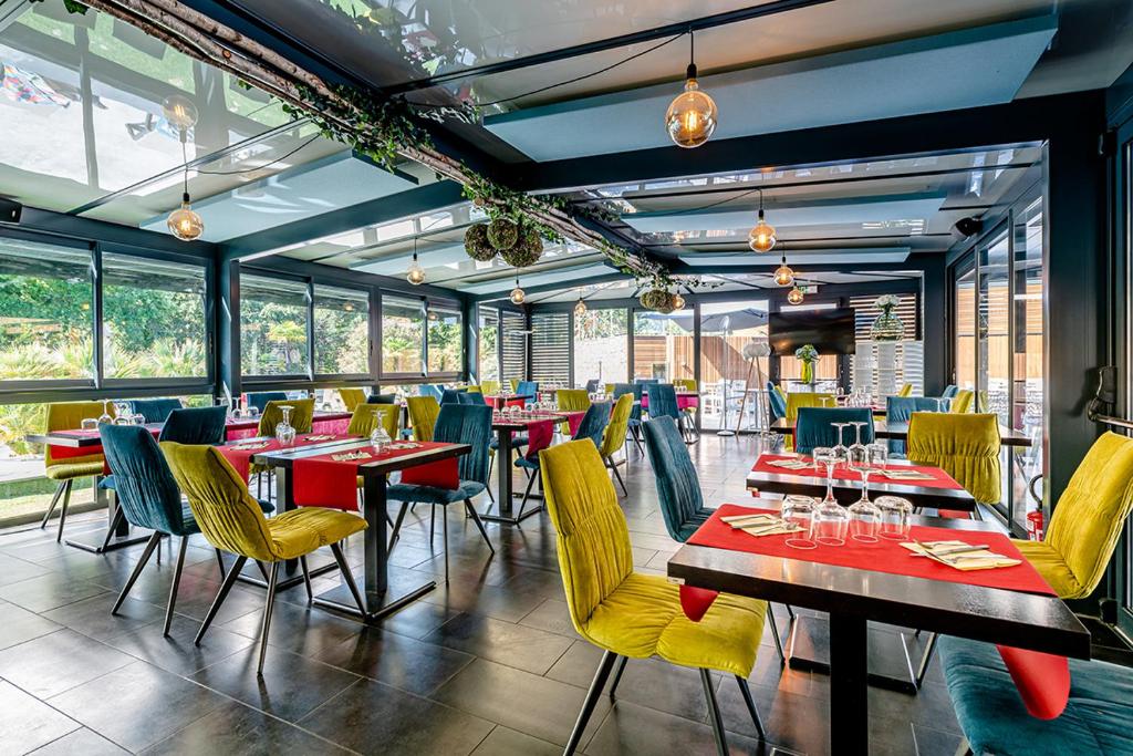 un restaurant avec des tables, des chaises et des fenêtres dans l'établissement Camping Domaine Les Oréades - Maeva Sélection, à Sanguinet