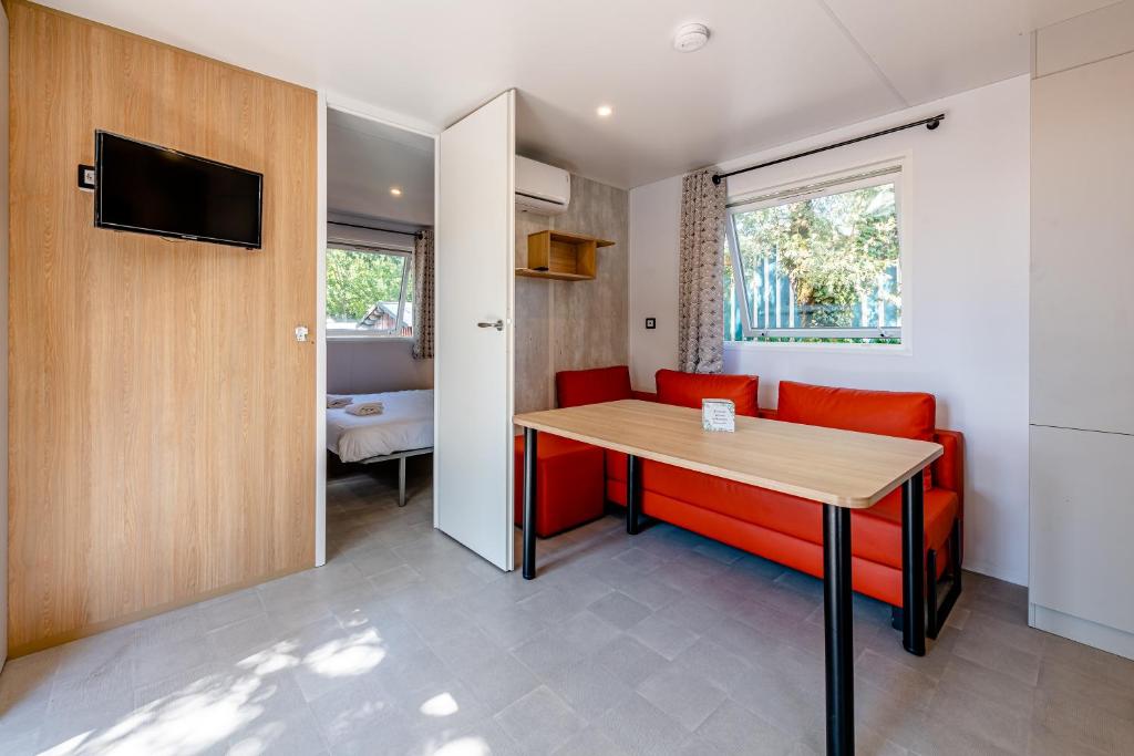 un salon avec une table et un canapé rouge dans l'établissement Camping Domaine Les Oréades - Maeva Sélection, à Sanguinet