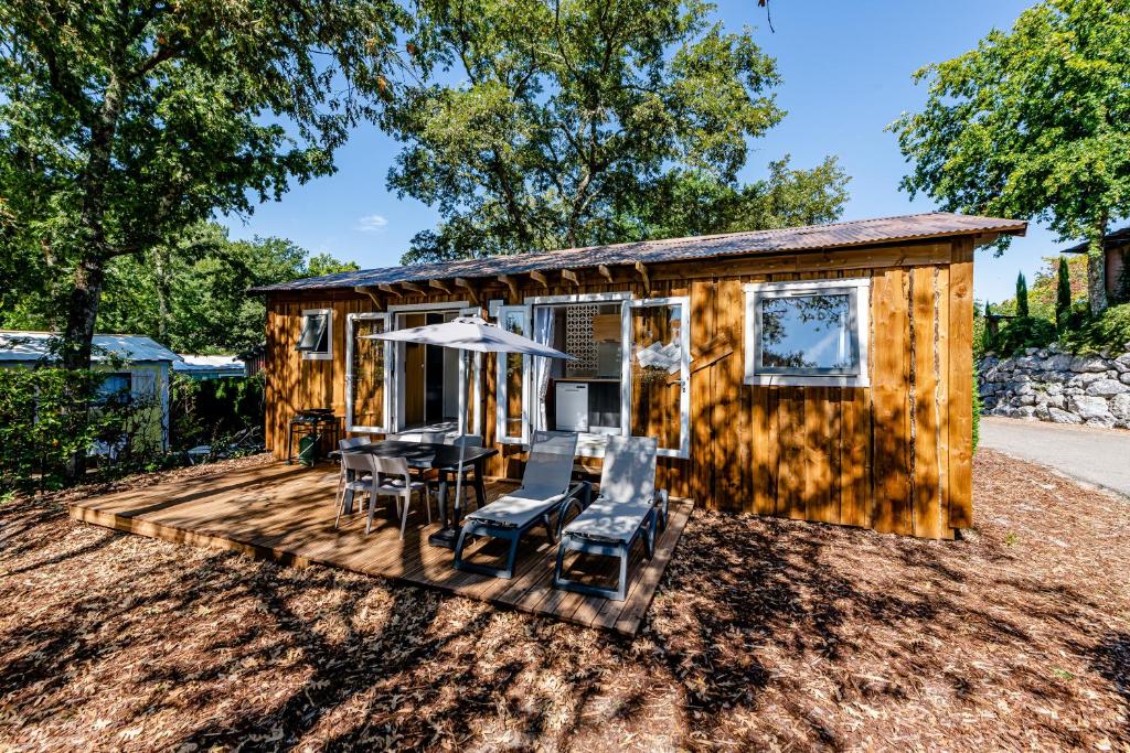 une petite maison avec une table et des chaises sur une terrasse dans l'établissement Camping Domaine Les Oréades - Maeva Sélection, à Sanguinet