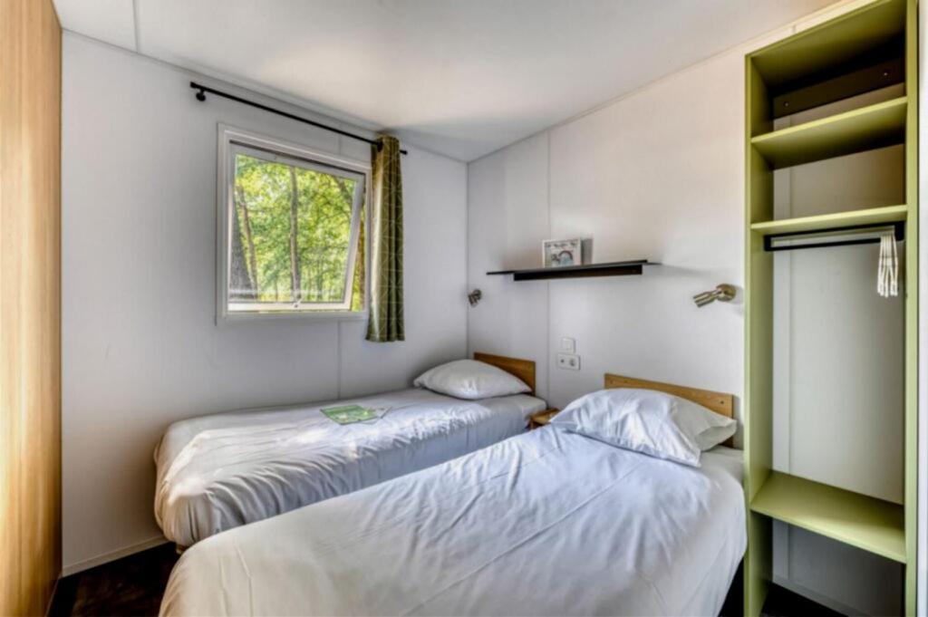 deux lits dans une petite pièce avec une fenêtre dans l'établissement Camping Domaine Les Oréades - Maeva Sélection, à Sanguinet 37 autres photos