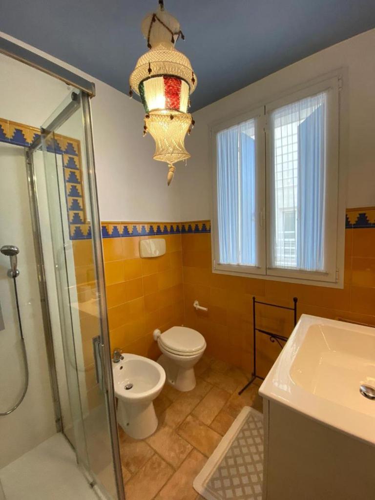 La salle de bains est pourvue de toilettes, d'une douche et d'un lustre. dans l'établissement Residence Ambra, à Lido di Jesolo 55 autres photos