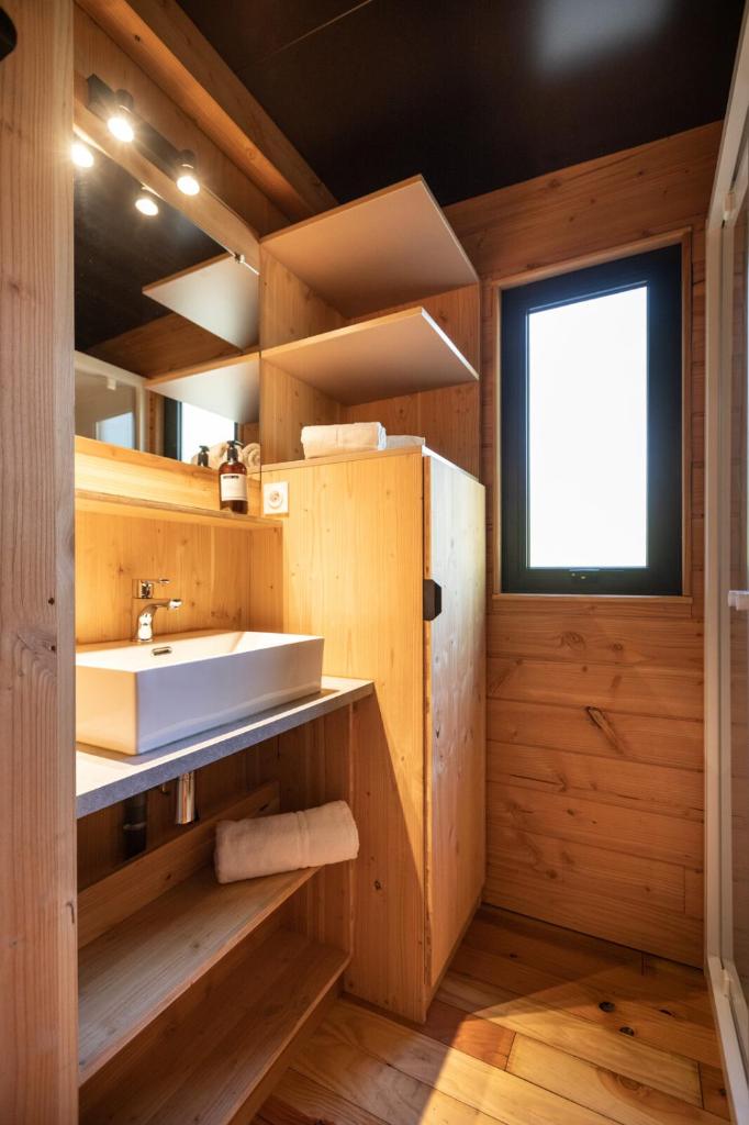 une salle de bain avec un lavabo blanc et une fenêtre dans l'établissement Huttopia Les Falaises - Normandie, à Saint-Pierre-en-Port