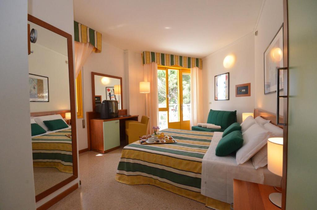 une chambre avec deux lits et un miroir dans l'établissement Hotel Luna, à Bibione