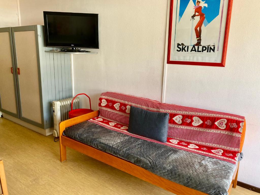 Cette chambre comprend un canapé rouge et une télévision. dans l'établissement SuperDévoluy, Résidence le Bois D'Aurouze, à Saint-Étienne-en-Dévoluy