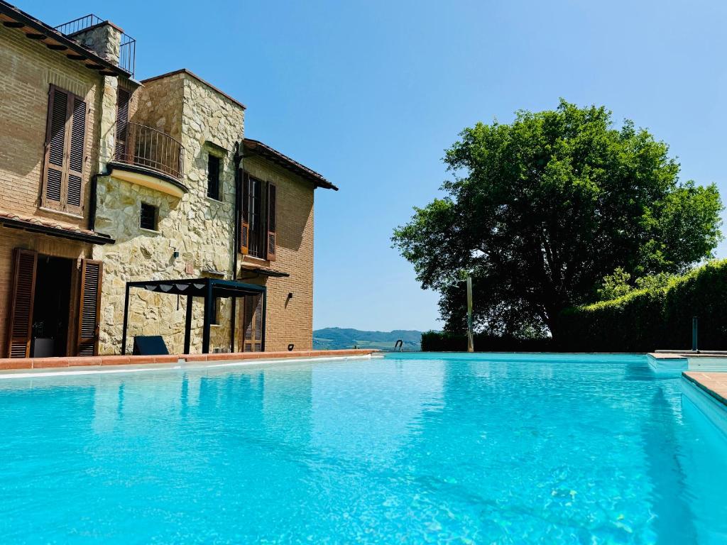 une grande piscine bleue à côté d'un immeuble dans l'établissement Libertas Tuscan Hideaway, à San Sano