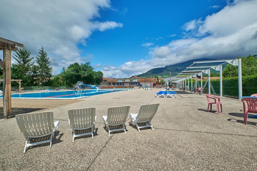 un groupe de chaises assises à côté d'une piscine dans l'établissement Caravane Tente 2 places, à Mens