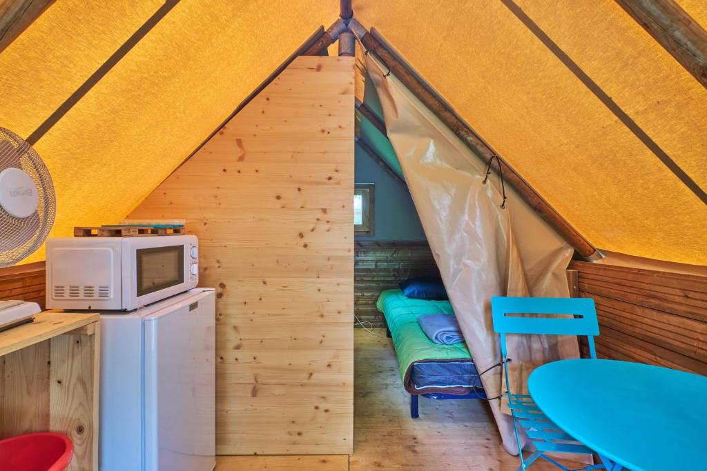 Cette chambre comprend une tente avec un four micro-ondes et une table. dans l'établissement Caravane Tente 2 places, à Mens
