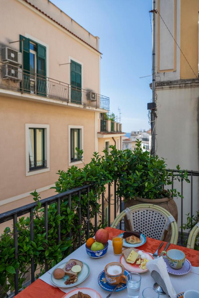 une table avec des assiettes de nourriture sur un balcon dans l'établissement Hotel Antica Repubblica in Amalfi center at 100mt from the sea, à Amalfi