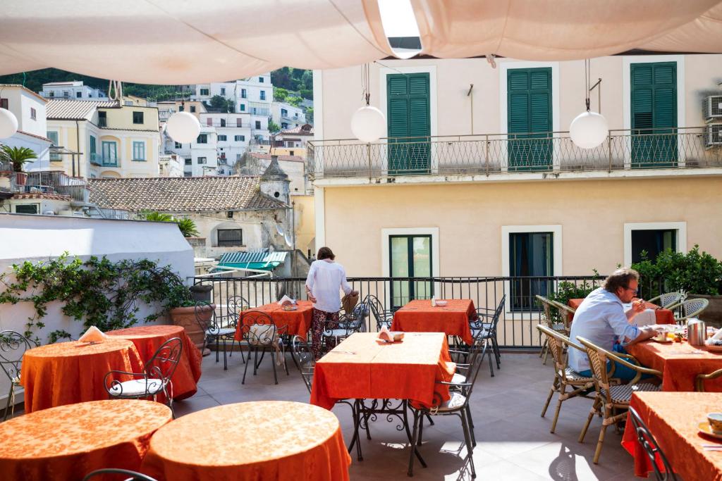 un patio extérieur avec des tables, des chaises et des bâtiments dans l'établissement Hotel Antica Repubblica in Amalfi center at 100mt from the sea, à Amalfi