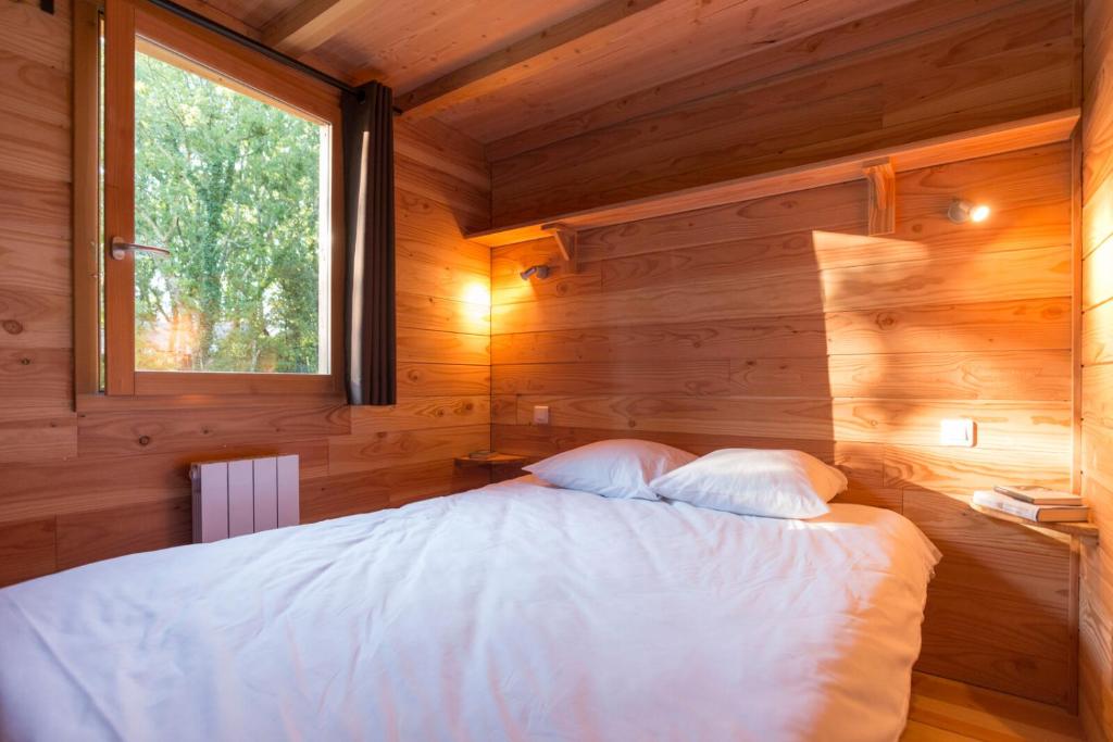 Ce lit se trouve dans une chambre en bois dotée d'une fenêtre. dans l'établissement Huttopia Rambouillet, à Rambouillet