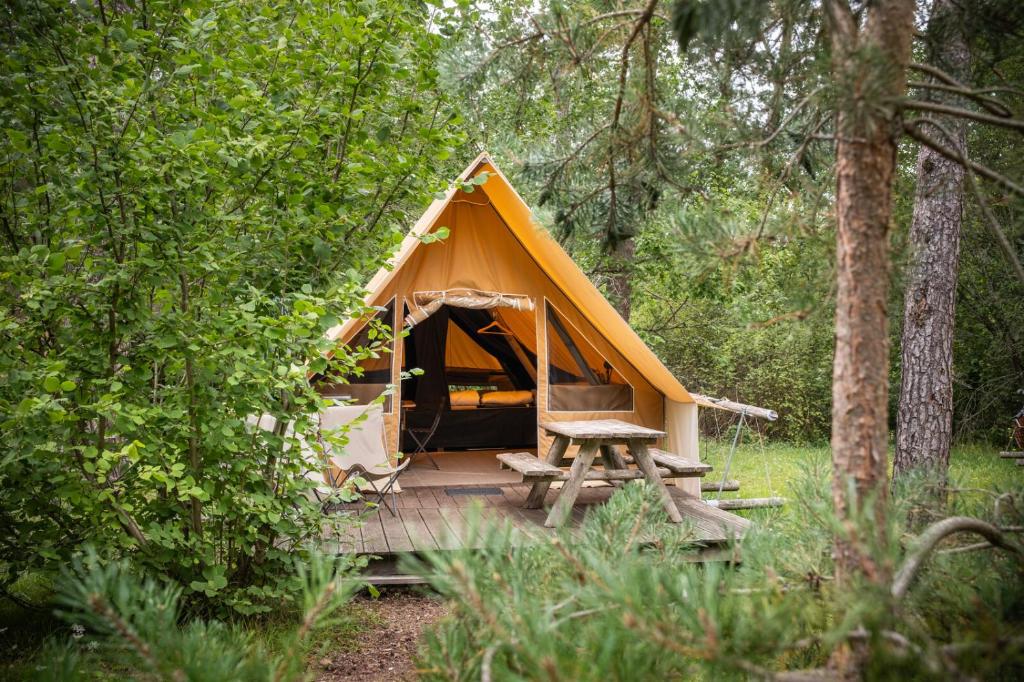 une tente avec une table de pique-nique dans les bois dans l'établissement Huttopia Rambouillet, à Rambouillet