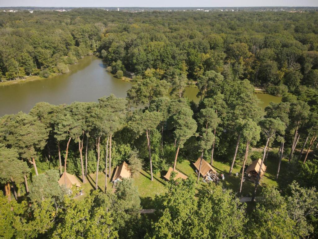 une vue aérienne sur une rivière avec des maisons et des arbres dans l'établissement Huttopia Rambouillet, à Rambouillet
