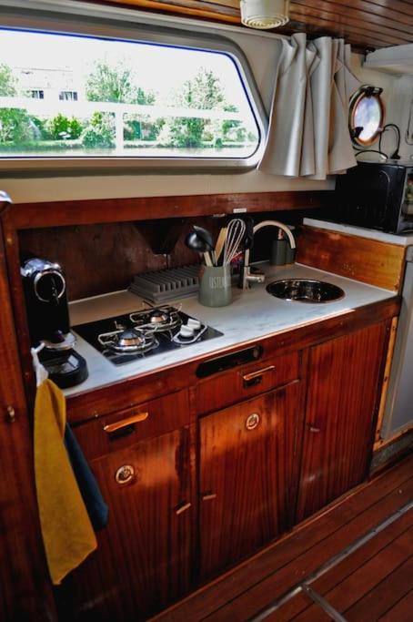Il comprend une petite cuisine avec une cuisinière et une fenêtre. dans l'établissement C'la Vie - Proche Fontainebleau - Bateau, à Nemours 15 autres photos