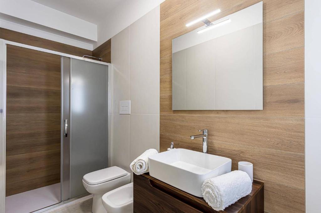 une salle de bain avec un lavabo, des toilettes et un miroir dans l'établissement Villa Ares by Villa Plus, à Santa Maria Del Focallo