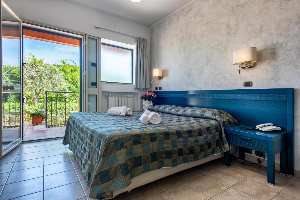une chambre d'hôtel avec un lit et un balcon dans l'établissement Hotel Baia Del Capitano, à Cefalù