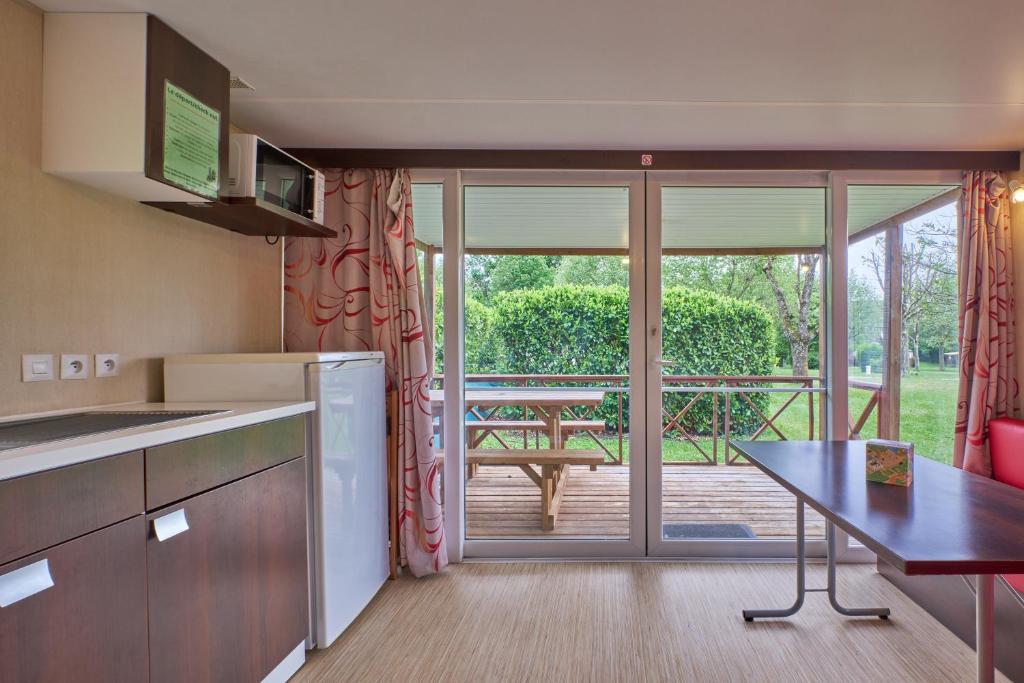 une cuisine avec une table et une vue sur un patio dans l'établissement Mobil Home 4 personnes 208, à Mens