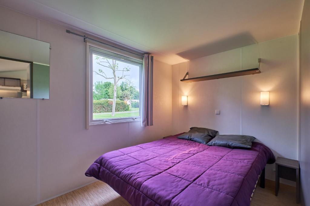 une chambre avec un lit violet et une fenêtre dans l'établissement Mobil Home 4 personnes 201, à Mens