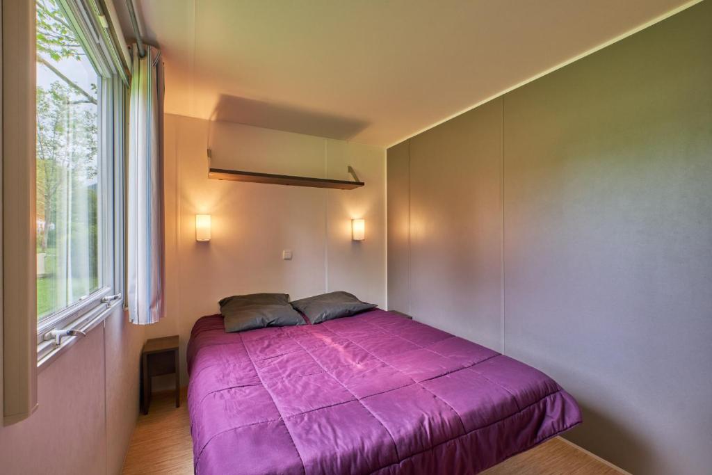- un lit violet dans une chambre avec fenêtre dans l'établissement Mobil Home 4 personnes 201, à Mens 18 autres photos