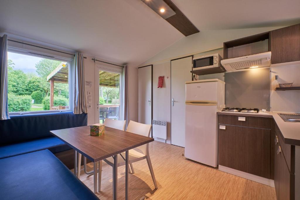 une cuisine avec une table et une petite cuisine avec une table et une table dans l'établissement Mobil Home 4 personnes 201, à Mens