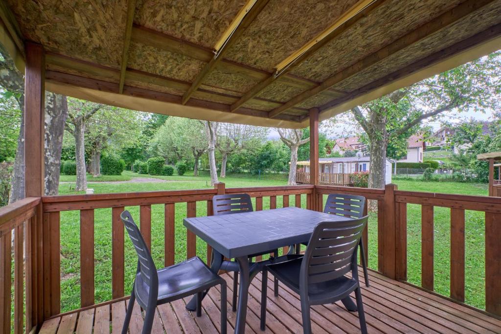 une terrasse en bois avec une table et des chaises dessus dans l'établissement Mobil Home 4 personnes 202, à Mens