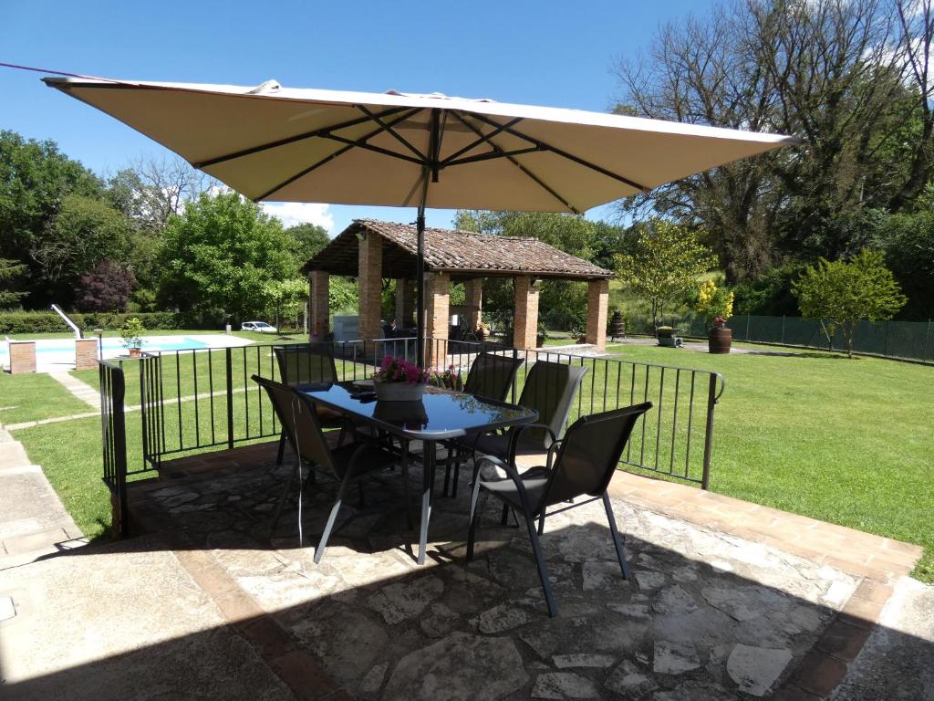 - une table et des chaises sous un parasol dans la cour dans l'établissement Scappo in Umbria, Casale Piccino, à Collicello