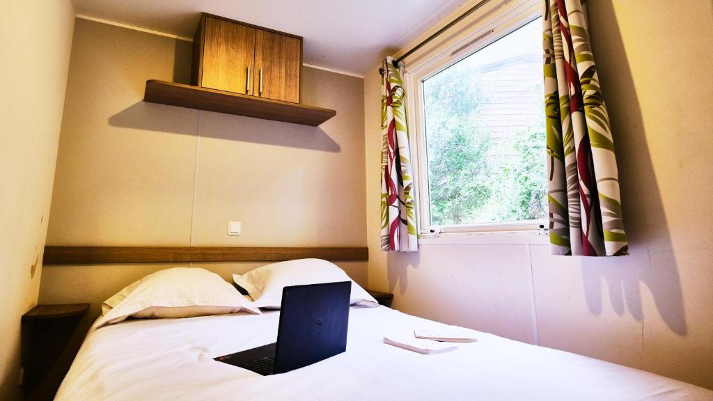 - un ordinateur portable assis sur un lit avec une fenêtre dans l'établissement Camping de la Vallée Heureuse, à Orgon