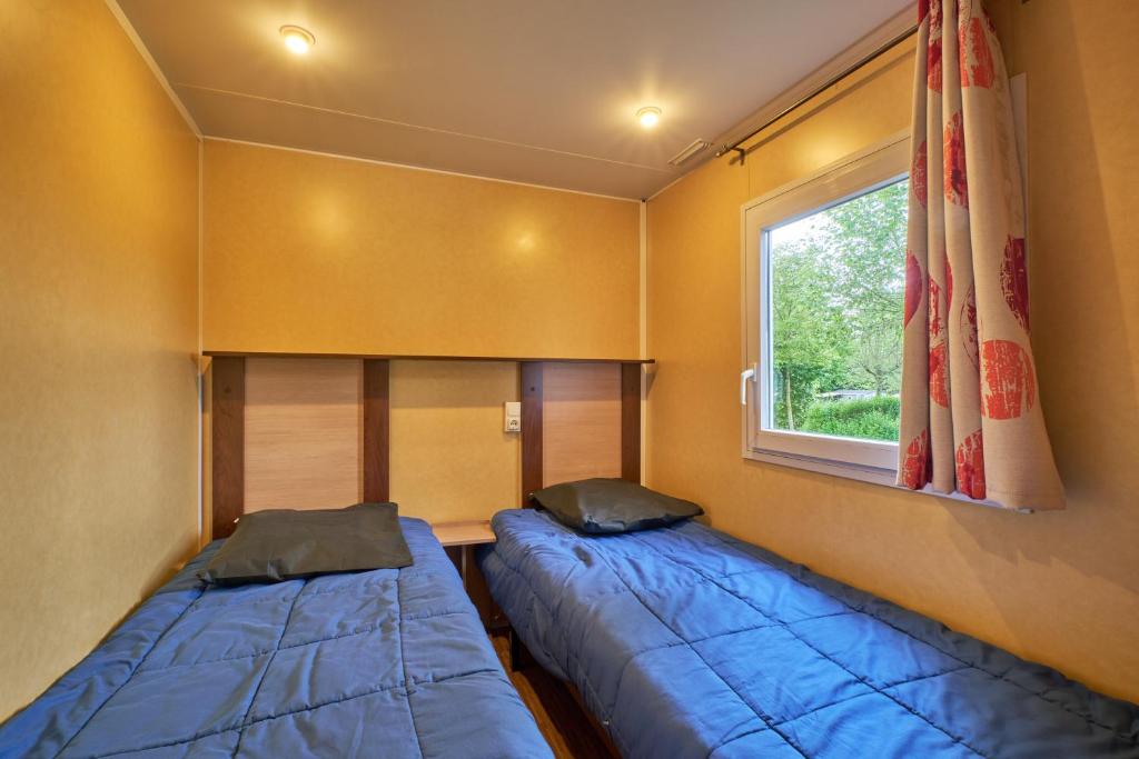 deux lits dans une petite pièce avec une fenêtre dans l'établissement Mobil Home 5 personnes 210, à Mens 17 autres photos