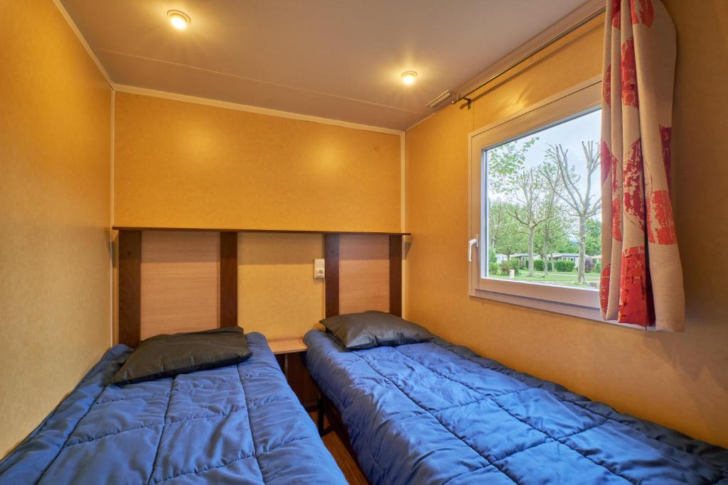 deux lits dans une petite pièce avec une fenêtre dans l'établissement Mobil Home 5 personnes 209, à Mens 15 autres photos