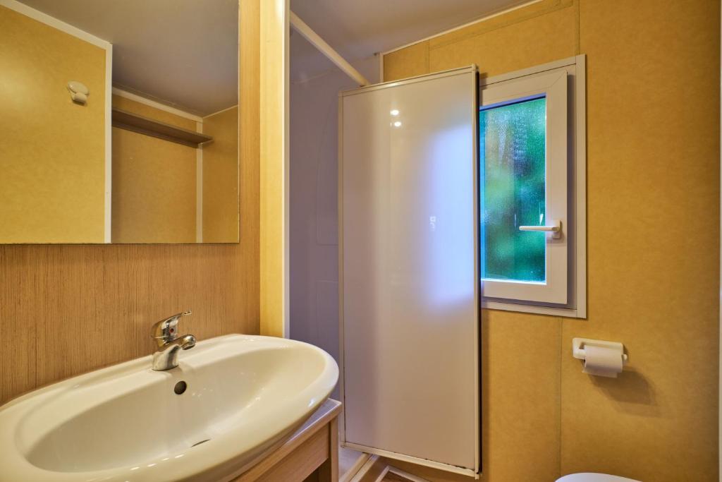 une salle de bain avec un lavabo, un miroir et une douche dans l'établissement Mobil Home 5 personnes 209, à Mens
