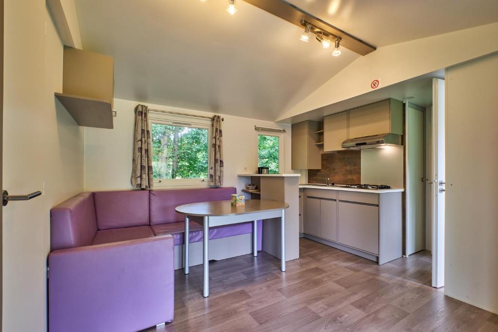 une cuisine avec un canapé violet et une table dans l'établissement Mobil Home 6 personnes 205, à Mens