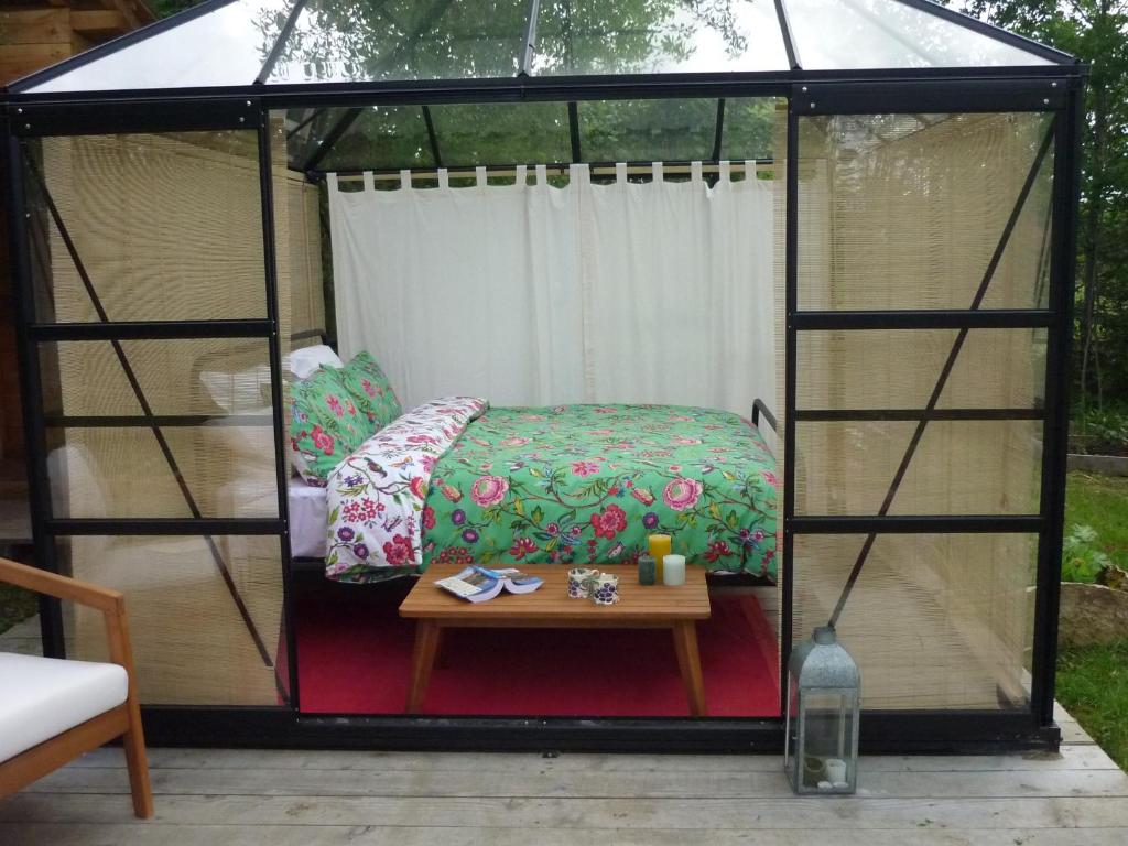 un lit et une table dans un gazebo dans l'établissement Le jardin secret, à Semur-en-Auxois