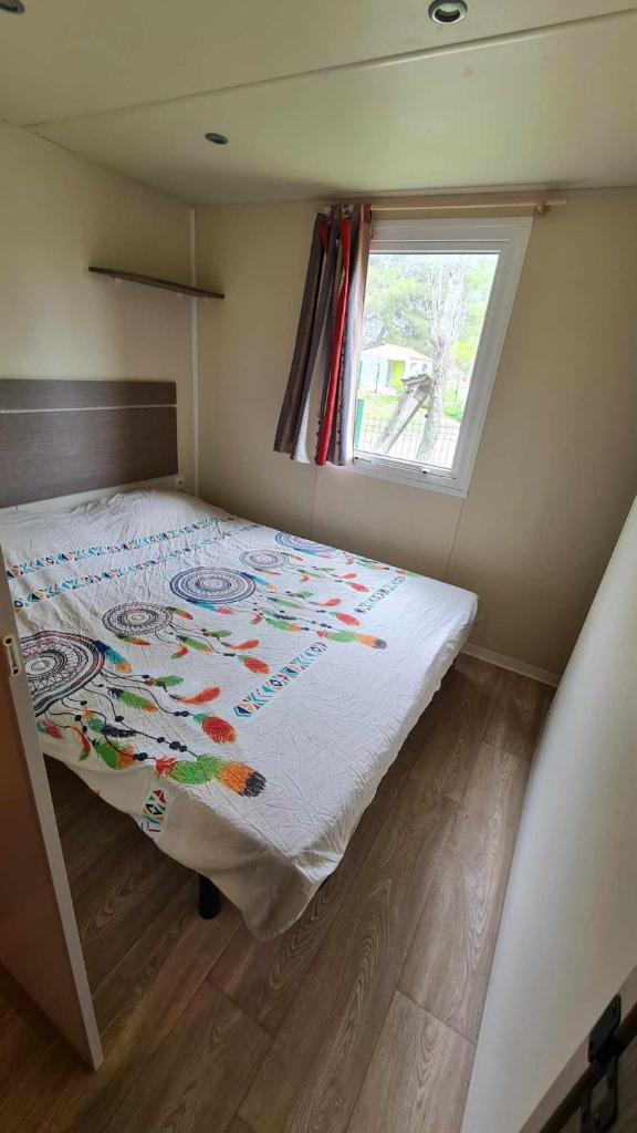 un lit dans une petite pièce avec une fenêtre dans l'établissement Mobil Home au calme Camping 4 Cadenet, à Cadenet