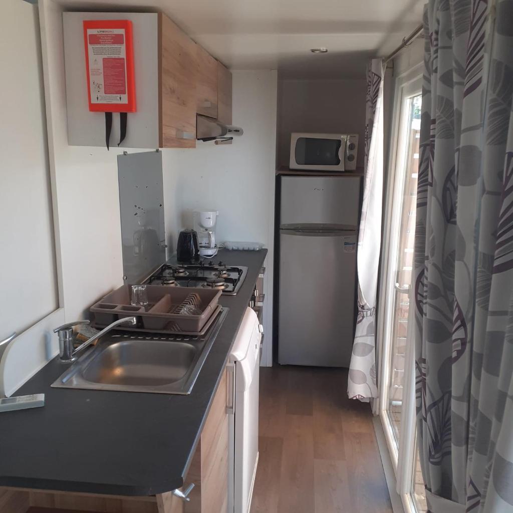 une petite cuisine avec un évier et une cuisinière dans l'établissement Camping les Salins de la Gardiole, à Vic-la-Gardiole