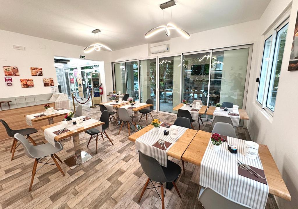 un restaurant avec des tables et des chaises dans une salle dans l'établissement chiAma Hotel, à Rimini