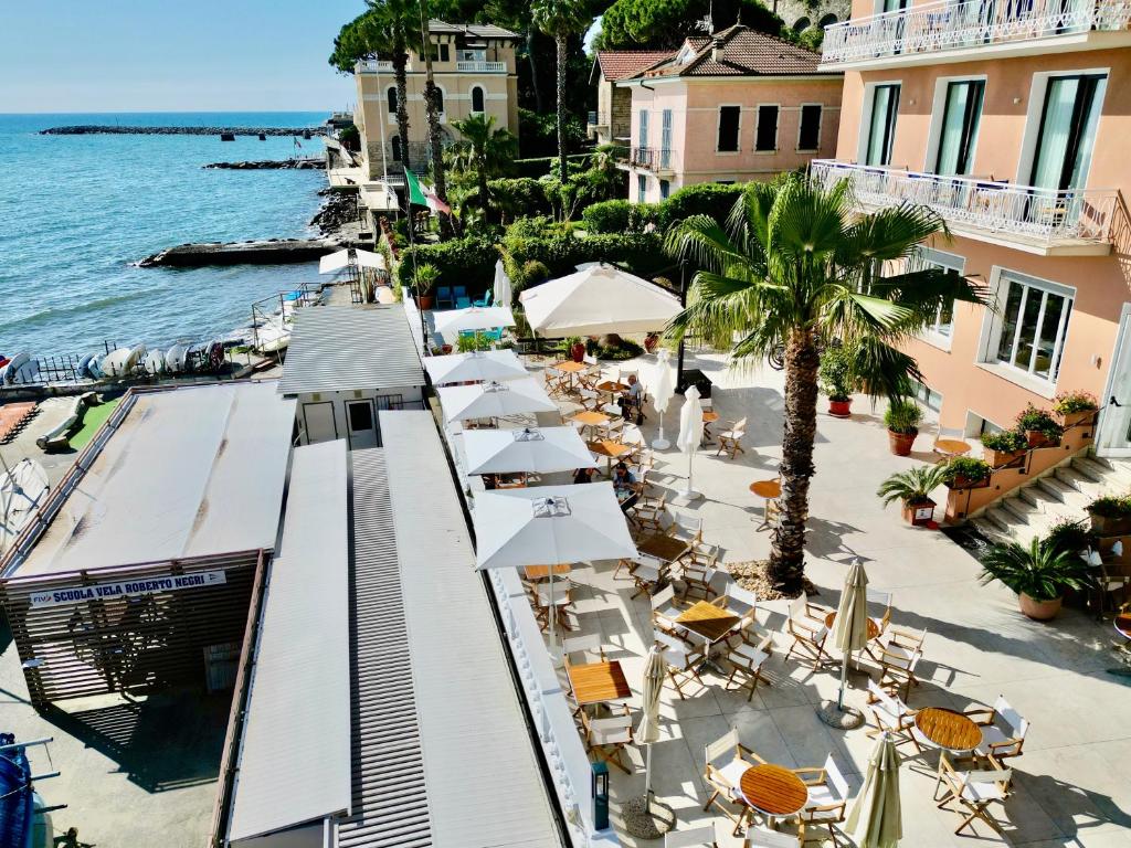 un restaurant en plein air avec des chaises et des parasols au bord de l'eau dans l'établissement Hotel Golfo e Palme, à Diano Marina