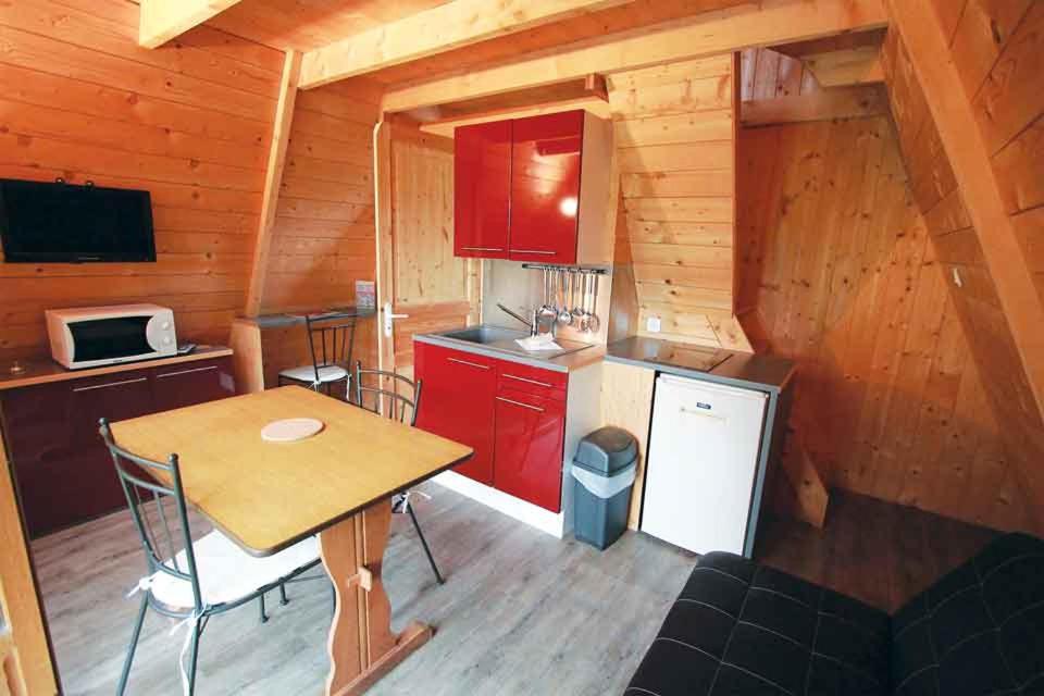 une cuisine avec des armoires rouges et une table dans une cabine dans l'établissement Cerza Safari Lodge, à Hermival-les-Vaux 23 autres photos